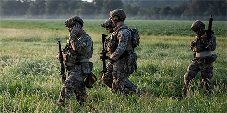 Imagen que muestra cuatro soldados modernos en una zona cubierta de hierba, completamente armados y con orejeras tácticas.
