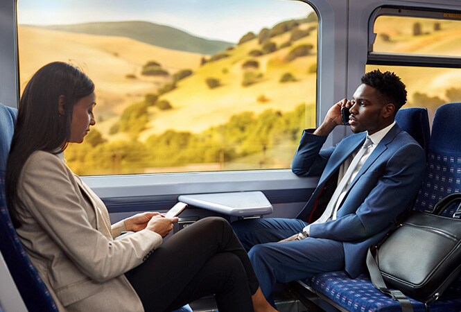 Pasajeros sentados en el interior de un vagón de tren que disfrutan de una mayor comodidad y climatización.
