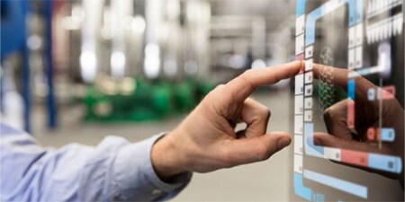 Trabajador de fábrica utilizando una pantalla táctil en la línea de montaje.
