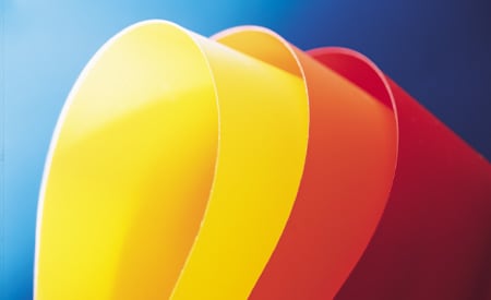 Muestras curvas de láminas de colores homogéneos amarillo, naranja y rojo sobre un fondo azul.
