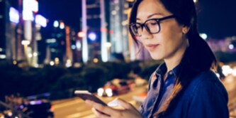 mujer mirando un teléfono sobre el horizonte de la ciudad
