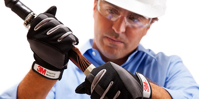 Trabajador con equipo de seguridad inspeccionando un cable eléctrico
