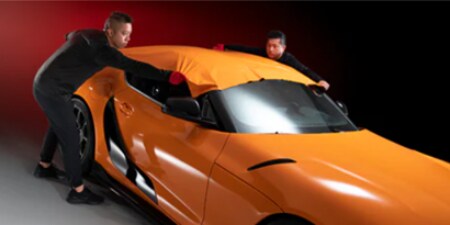 dos instaladores aplicando lámina naranja en un vehículo
