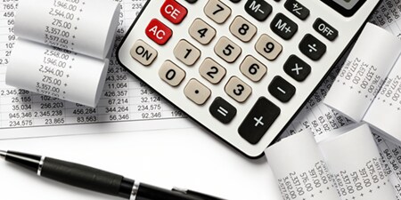 Calculadora rodeada de recibos impresos y gráficos.
