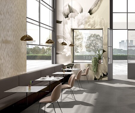 Interior de una cafetería con tonos neutros y un mural floral impreso sobre una lámina gráfica que cubre las paredes.

