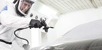 Técnico de pintura pulverizando sobre un vehículo
