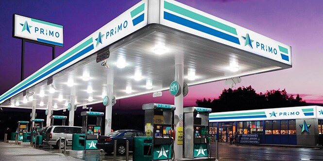 Gasolinera con imágenes y señales vívidas retroiluminadas en color verde y azul
