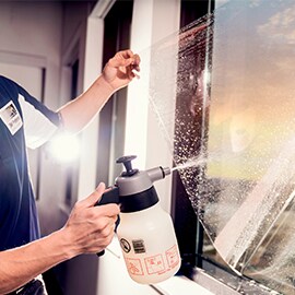 Una persona instalando una lámina para ventanas de edificios 3M™