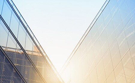 Sol brillante brillando sobre edificios angulosos cubiertos de ventanas
