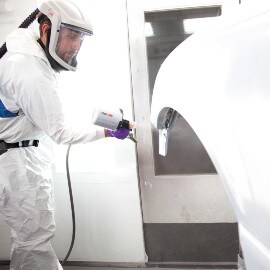 Pintor pulverizando una parte de la carrocería de una utomóvil con sistema de pulverización de 3M