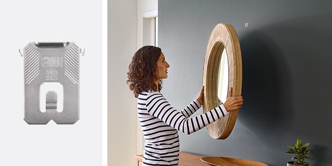 Mujer colgando un espejo en una pared con el gancho para cuadros en pared de cartón-yeso 3M CLAW™

