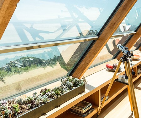 Interior de una casa con grandes ventanas en ángulo con vistas de la playa
